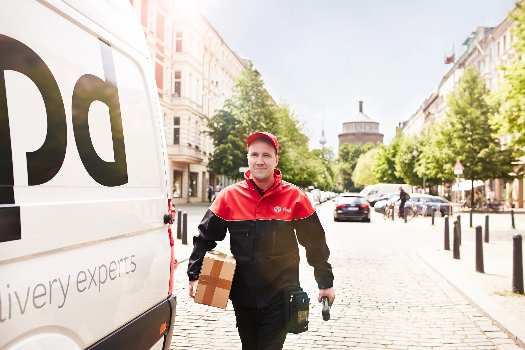 Jeffrey Wipprecht als dpd-Zusteller mit Paket auf einer Berliner Straße
