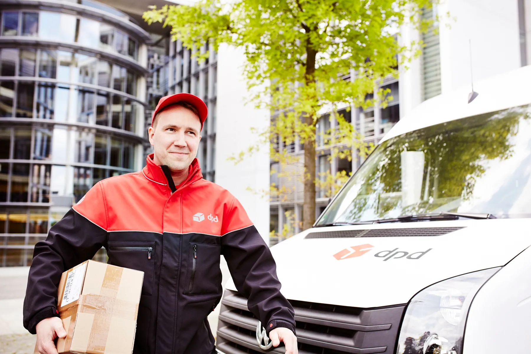 dpd-Zusteller mit Paket vor dem Lieferwagen